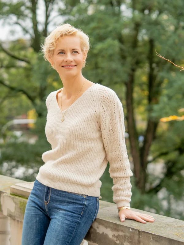Monika Milejska opierająca się o murek na tle zieleni